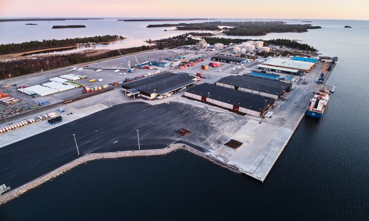 Vy över en hamn med utbyggd kajdel. Klar, blå himmel och skarp horisont i bakgrunden. Vattnet ligger stilla och kajen sträcker sig ut i perspektiv mot horisonten.